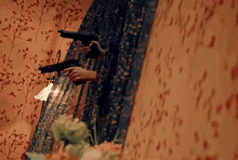 a woman in a dress is holding a gun in a room with flowers on the wall .
