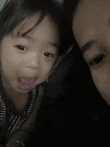 a little girl sticking her tongue out next to a man 's head