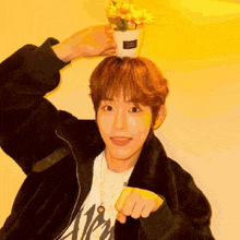 a young man holds a potted plant on his head that says flower buddy