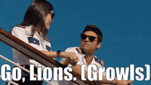 a man and a woman standing on a balcony with the words go lions growls