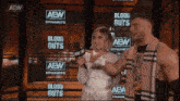 a man and a woman standing in front of a wall that says aew