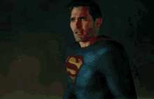 a man in a superman costume is making a funny face and looking at the camera .