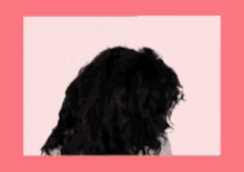 a woman with curly hair is standing in front of a pink and white frame .
