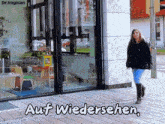 a woman walking in front of a store with the words auf wiedersehen
