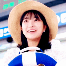 a woman wearing a straw hat is smiling and holding a blue and white life preserver