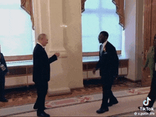a man in a suit is shaking hands with another man in a suit