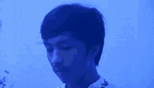 a young man is drinking a glass of water in a blue room .