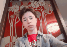 a young man taking a selfie with a red background and a shirt that says b.a.w.