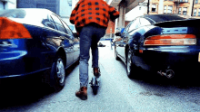 a man in a plaid jacket is riding a scooter on a city street