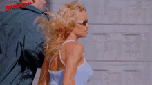 a woman wearing sunglasses stands next to a man with the word baywatch on the bottom
