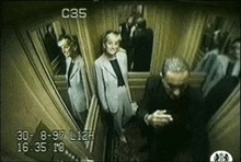 a man and a woman are standing in an elevator with the number c35 on it