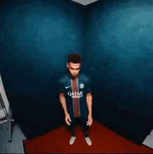 a man is standing in a room with a blue wall and a red rug .