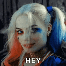 a woman in a harley quinn costume says " hey "