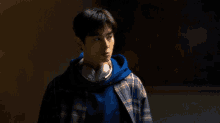 a young man wearing headphones and a plaid shirt is standing in a dark room .