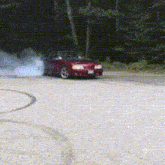 a red car is drifting down a road with smoke coming out of the tires