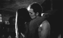 a man and a woman are kissing in a black and white photo .