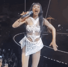 a woman in a white dress is singing into a microphone on stage
