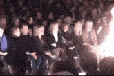 a group of people sitting in a dark room with a light shining through the middle