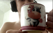 a man wearing headphones is holding a mug with a cow on it