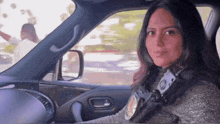 a woman is sitting in a car with a badge on her chest that says ' s.p.d. '