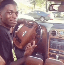 a young man is driving a bentley car