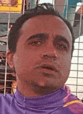 a man in a purple shirt is looking at the camera .