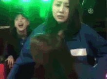 a woman in a blue uniform is standing in a dark room with green lights behind her .