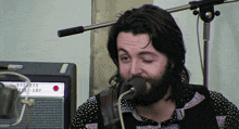 a man with a beard is singing into a microphone in front of a bassman amp