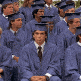 a man in a graduation cap and gown stands in a crowd