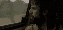 a man with a beard is looking out a window