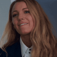 a woman with long blonde hair is smiling and wearing a suit and white shirt