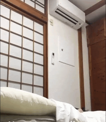 a white air conditioner is mounted to the wall above a window 