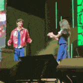 a man and a woman are dancing on a stage with a green background