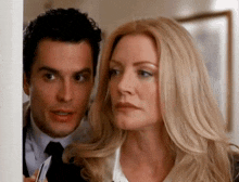 a man and a woman are standing next to each other looking at something