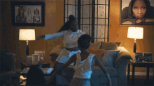 a group of people are dancing in a living room with a picture of a woman on the wall behind them