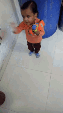 a little boy is standing on a tiled floor holding a toy car that says ' disney ' on it