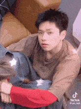 a tiktok video of a young man sitting on the floor with a couch in the background