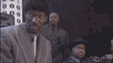 a man in a suit and tie is laughing in a dark room .