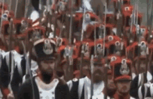 a large group of soldiers are marching in a parade with their swords in the air .