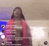 a woman in a red jacket is standing in front of a computer screen with a bunch of people watching .