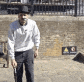 a man wearing a top hat and mustache is walking down a sidewalk