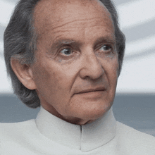 a close up of a man 's face wearing a white collared shirt