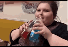 a woman is drinking a blue and red beverage from a glass .