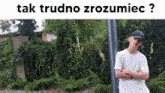 a man with his arms crossed is standing in front of a fence with the words tak trudno zrozumiec written above him