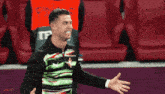 a man wearing a green and black shirt with a red t on it