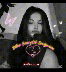 a black and white photo of a girl with a heart on her shirt .
