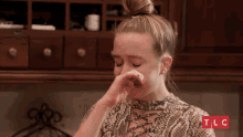 a woman in a snake print shirt is crying with tlc written on the bottom right
