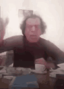 a man with glasses is sitting at a table with a cup of coffee .
