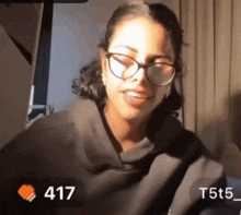 a woman wearing glasses and a black shirt has a heart next to 417