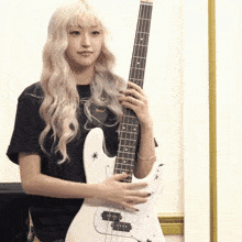 a blonde woman is holding a white bass guitar with a star on the neck
